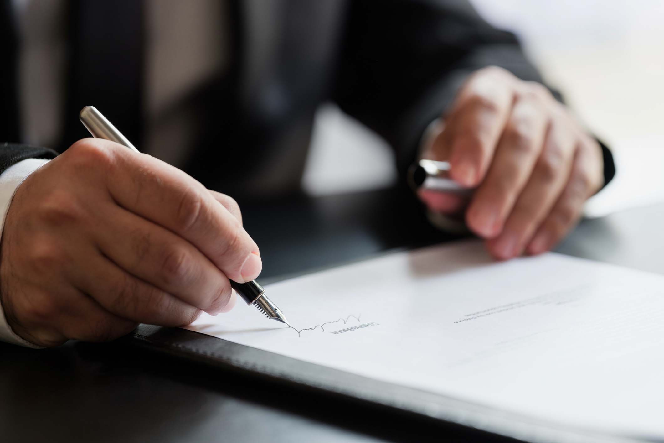 Businessperson signing piece of paper Businessperson signing piece of paper