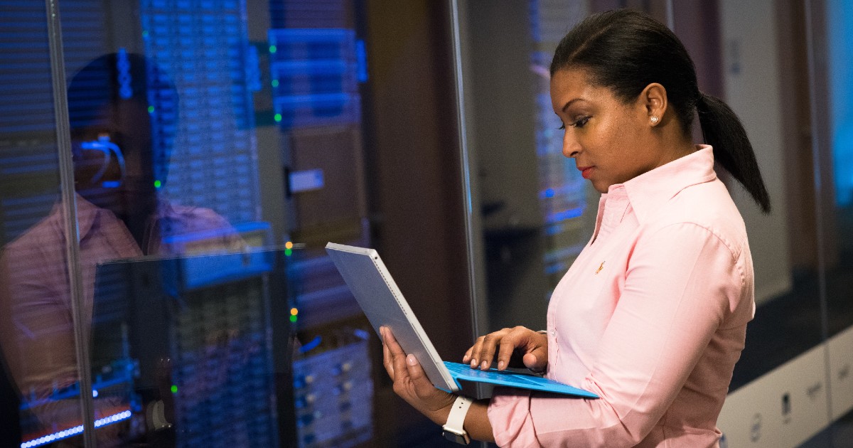 IT checks info on laptop in front of IT room